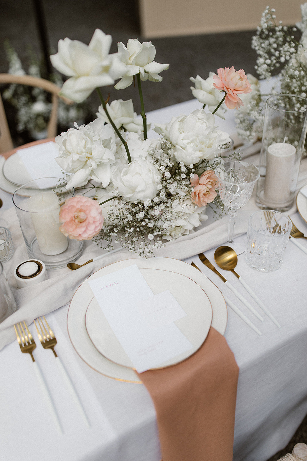 Hochzeitskonzept mit eleganter Blumendekoration in Weiß und Rosa, goldenen Besteckteilen und Menükarte.
Beschreibung: Dieses edle Hochzeitskonzept kombiniert zarte Blumen in Weiß und Rosa mit einem stilvollen Gedeck aus goldenen Besteckteilen und einer minimalistischen Menükarte. Die harmonische Farbgebung und die hochwertigen Details verleihen dem Tisch einen romantisch-luxuriösen Look.