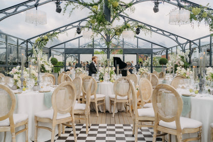 Luxuriöse und ästhetische Hochzeitsdekoration in einer stilvollen Orangerie mit eleganter Tischdekoration, weißen Blumen und hängenden, grünen Pflanzen.Diese edle Hochzeitslocation in einer Orangerie verbindet Natur und Eleganz. Die mit floralen Akzenten dekorierten Tische, die stilvollen hellen Stühle und die modernen Lichtinstallationen schaffen eine exklusive, luxuriöse Atmosphäre. Ideal für Paare, die eine besondere Hochzeitsinspiration suchen.