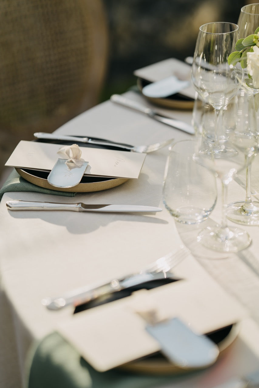 Elegantes Tischgedeck mit eleganter Dekoration und personalisierten Gastgeschenken bei einer luxuriösen Hochzeit in Berlin. Das schlichte, aber edle Tischgedeck besticht durch hochwertige Materialien, klare Linien und dezente Details. Personalisiert verpackte Gastgeschenke verleihen der festlichen Tafel eine persönliche Note, während die eleganten Gläser und Bestecke die exklusive Atmosphäre dieser stilvollen Hochzeitsfeier unterstreichen. Ideal für eine Hochzeit, die minimalistischen Luxus sucht.