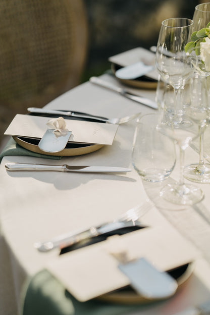 Elegantes Tischgedeck mit eleganter Dekoration und personalisierten Gastgeschenken bei einer luxuriösen Hochzeit in Berlin. Das schlichte, aber edle Tischgedeck besticht durch hochwertige Materialien, klare Linien und dezente Details. Personalisiert verpackte Gastgeschenke verleihen der festlichen Tafel eine persönliche Note, während die eleganten Gläser und Bestecke die exklusive Atmosphäre dieser stilvollen Hochzeitsfeier unterstreichen. Ideal für eine Hochzeit, die minimalistischen Luxus sucht.