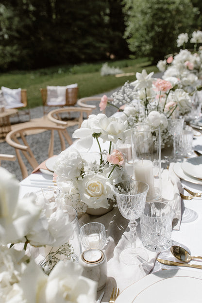 Romantisch, ästhetische Hochzeitstischdekoration im Garten mit weißen Blumen, edlen Gläsern und zarten Details. Diese romantische Tischdekoration für eine Gartenhochzeit besticht durch weiße Blumenarrangements, edle Kristallgläser und fein abgestimmte Details. Die dezente Farbpalette und elegante Gestaltung sorgen für eine stilvolle Atmosphäre im Freien.